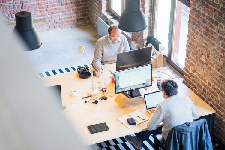 Dos personas trabajando en una oficina con varios monitores