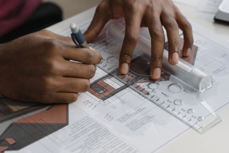 Manos revisando un plano técnico con reglas de dibujo