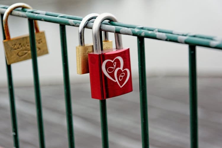 Candados con forma de corazón colgados de una reja