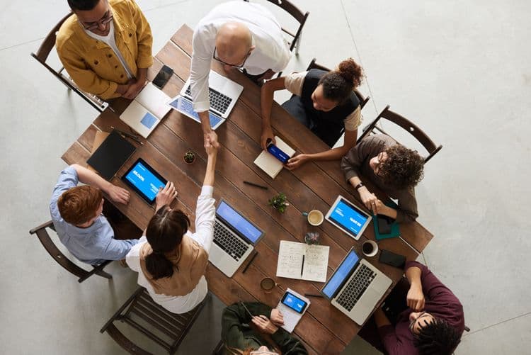 Equipo de varias personas trabajando juntas en una mesa con laptops